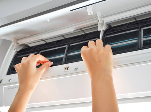 A person is cleaning the air conditioner with a brush.