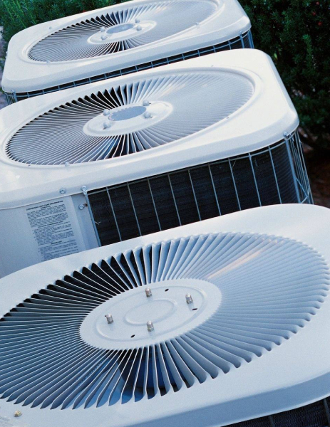 A row of air conditioners sitting outside in the sun.